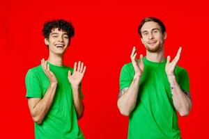 two men holding their heads in green T-shirts on a red background photo