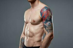 hombre con tatuajes en su brazos desnudo torso bombeo arriba abdominales rutina de ejercicio foto