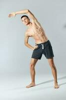 deporte hombre con bombeado arriba brazo músculos doblado a el lado en gris antecedentes ejercicio foto