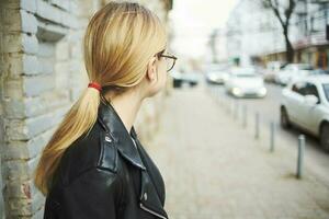 mujer caminando abajo el calle cerca el edificio en cuero chaqueta recortado ver foto