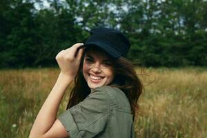 A woman straightens her cap on her head and laughs outdoors photo
