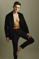 hermoso hombre en negro camisa soportes con doblado pierna posando modelos atractivo Mira foto