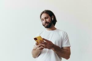 Man blogger holds a phone in his hands and communicates with people online in social networks with a smile and a white t-shirt on a white background photo