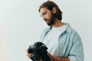 Man hipster photographer in a studio on a white background looking at the camera screen and setting it up for a photo shoot