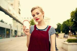 alegre mujer al aire libre caminando en vaso con Moda bebida foto