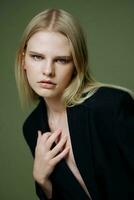 A close portrait of a blonde crossing her arms on her chest holding a jacket by the collar photo