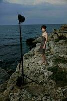 hermosa mujer en pie en piedras posando en playa vestir lujo foto