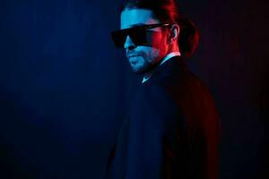 handsome man in a jacket posing self confidence sunglasses dark background photo