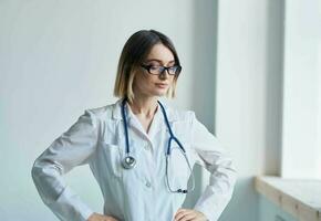 Professional doctor woman stands near the window and a stethoscope around her neck photo