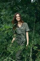 Woman in the forest near the green bushes a dazzling smile and a green jumpsuit green leaves photo