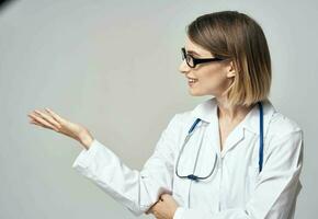 doctor with a stethoscope shows his hand to the side on a gray background Copy Space photo