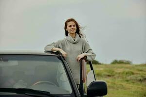 pretty woman with red hair in a sweater near the car nature unaltered photo