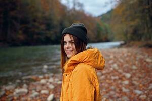 woman in a yellow jacket in the autumn forest fallen leaves river photo