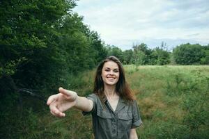 Woman in the field smile outstretched hands forward nature green trees photo