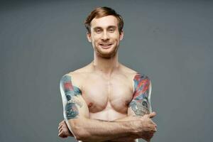 Cheerful man with an inflated muscular body tattoo on his arms posing photo