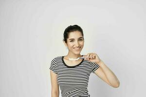 cheerful woman in a striped t-shirt toothbrush in hand isolated background photo