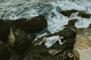 attractive woman with long hair in a white dress lying on a stone in a white dress unaltered photo