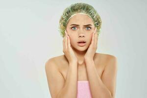 national woman in pink towel holding face photo