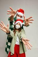 Cheerful young couple in medical masks Christmas life with hands together New Year photo
