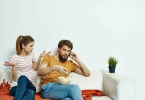 man and woman on the couch indoors chatting friends popcorn photo