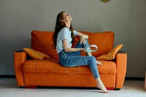 cheerful woman on the orange sofa listening to music with headphones Lifestyle photo