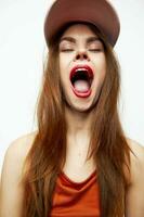 Woman in a cap Opens his mouth wide with fun emotions closed eyes orange dress photo