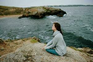 woman seated on the coast sweater landscape female relaxing photo