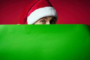handsome man in a christmas hat with green mockup red background photo