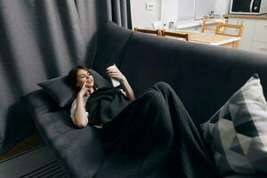 woman with phone in hand resting lying on the couch top view photo