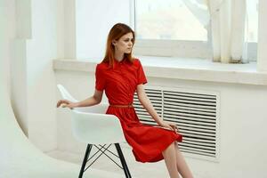 pretty woman in red dress posing on a chair elegant style photo