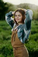 Portrait of a young girl on a summer day in the rays of the setting sun with a beautiful smile, dressed as a farmer and gardener photo