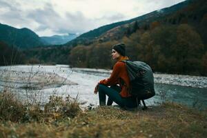 woman travels in the mountains near the river in the meadow in the forest rest relax photo