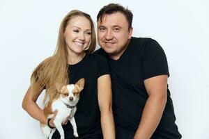 cheerful married couple in black T-shirts hugs a purebred small dog photo