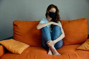 portrait of a woman in black protective masks sitting on the couch at home stay home concept photo