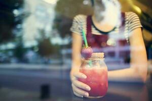 un mujer con un corto peinado se sienta en un café solo con un cóctel foto