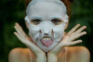 hermosa mujer cara máscara muestra lengua y sostiene manos cerca cara dermatología foto