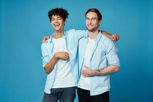 amigos abrazando en un azul antecedentes divertido pareo camisas blanco camiseta pantalones foto