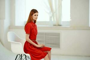 pretty woman in red dress posing on a chair luxury photo