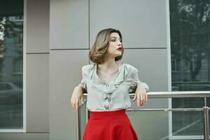 pretty blonde in a red skirt near a building on the street posing photo