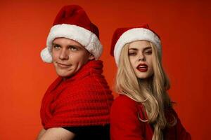 young couple in santa hats fun new year holiday red background photo