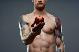 desnudo carrocero con bombeado músculos y tatuaje manzana en mano salud foto