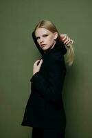 Serious strict attractive lady holding her hair posing isolated on a green background in the studio photo