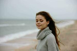 pretty woman red hair in a sweater by the ocean Happy female relaxing photo