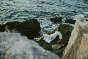 Barefoot woman lying on rocky coast with cracks on rocky surface view from above photo