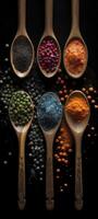 A row of wooden spoons filled with different types of spices on black background. photo