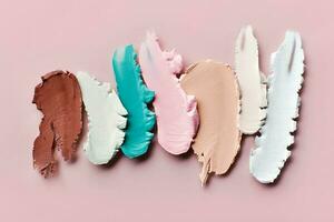 Samples of color correcting concealers Set on pink background. Swatch smears of cream makeup base photo