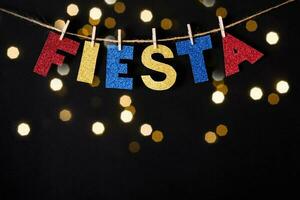 Fiesta word made of shiny paper and pins on black background and bokeh lights. Cinco de mayo concept photo