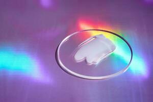 Smear of cream in petri dish on holographic background with iridescent highlights photo