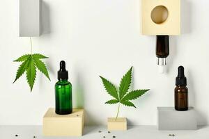 Different glass bottles with CBD oil and cannabis leaves on abstract geometric podiums. Cosmetics CBD oil concept photo