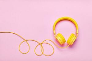 amarillo auriculares en rosado antecedentes. mínimo música concepto, plano poner, Copiar espacio foto